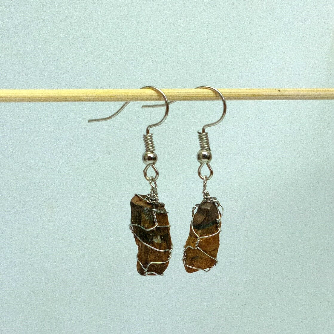 Pair of earrings with brown stone-like beads on a light blue background