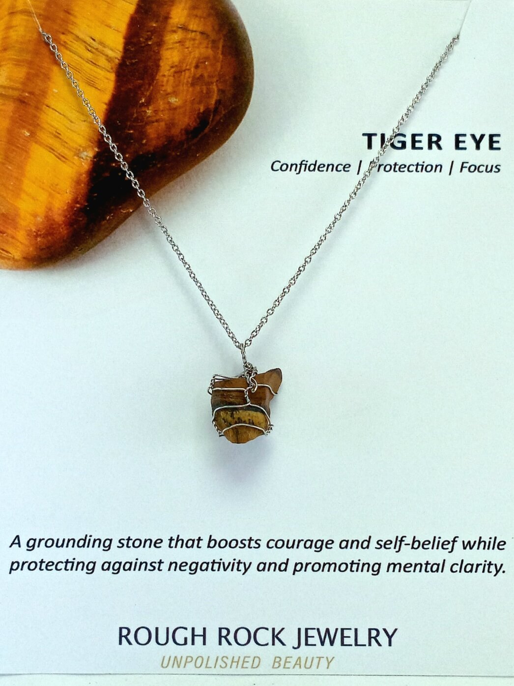 Tiger eye necklace on a white background with text about its properties and brand.