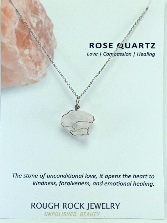 Rose quartz necklace with stone on a light blue background, featuring Rough Rock Jewelry branding.