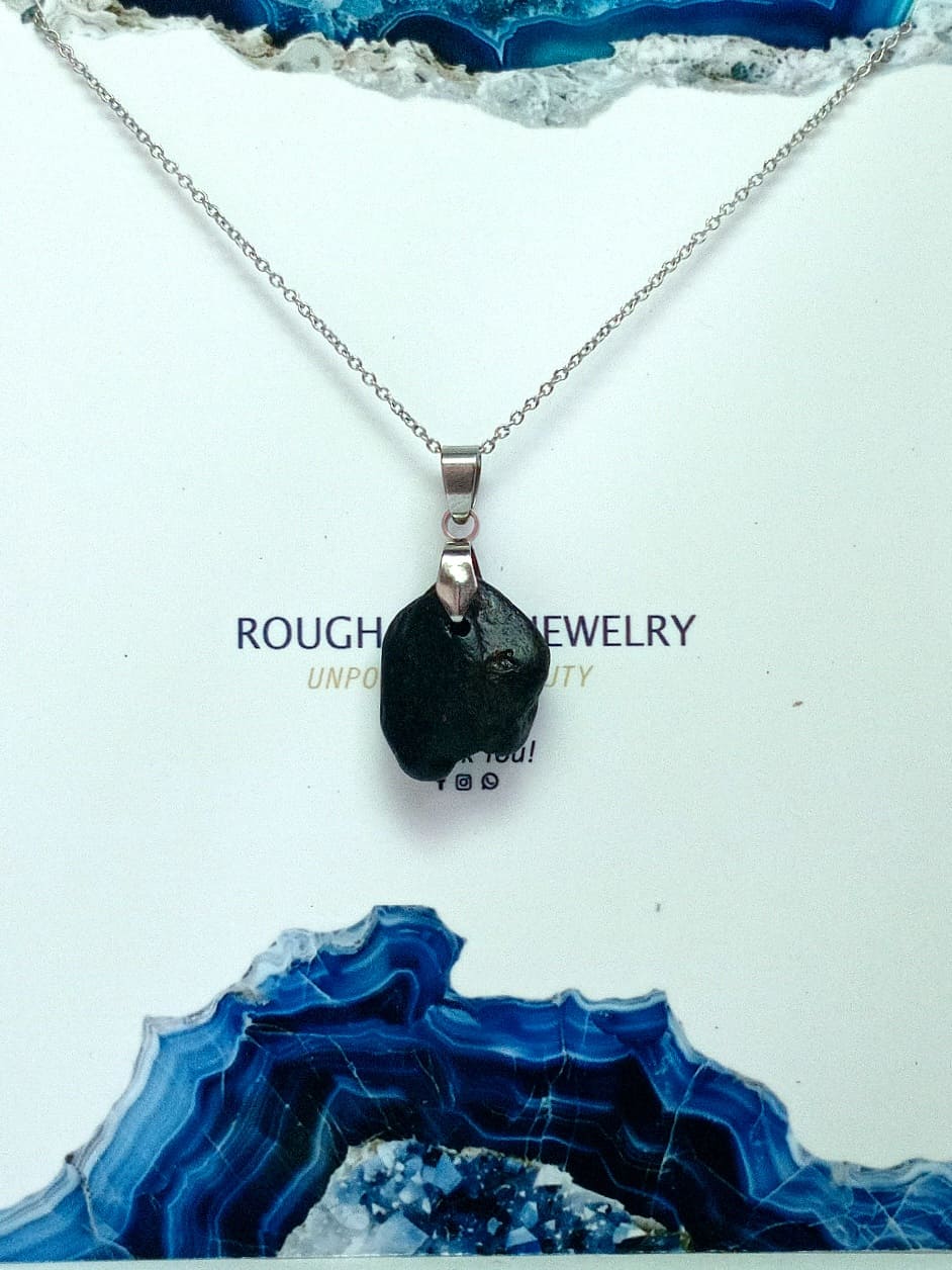 Necklace with a black pendant on a white surface with blue agate rock