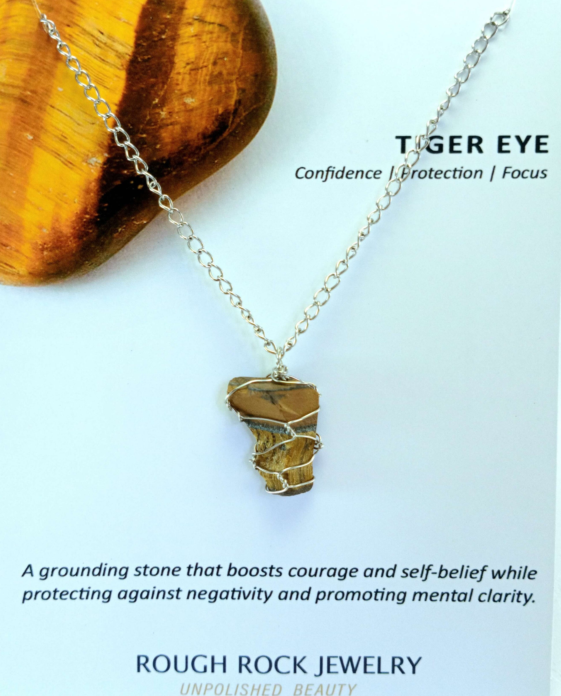 Tiger eye necklace on a stone with descriptive text about the stone's properties.